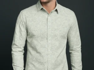 Man wearing a slim fit, full-sleeve shirt in a light sage green with a subtle micro print, paired with blue jeans against a dark background.