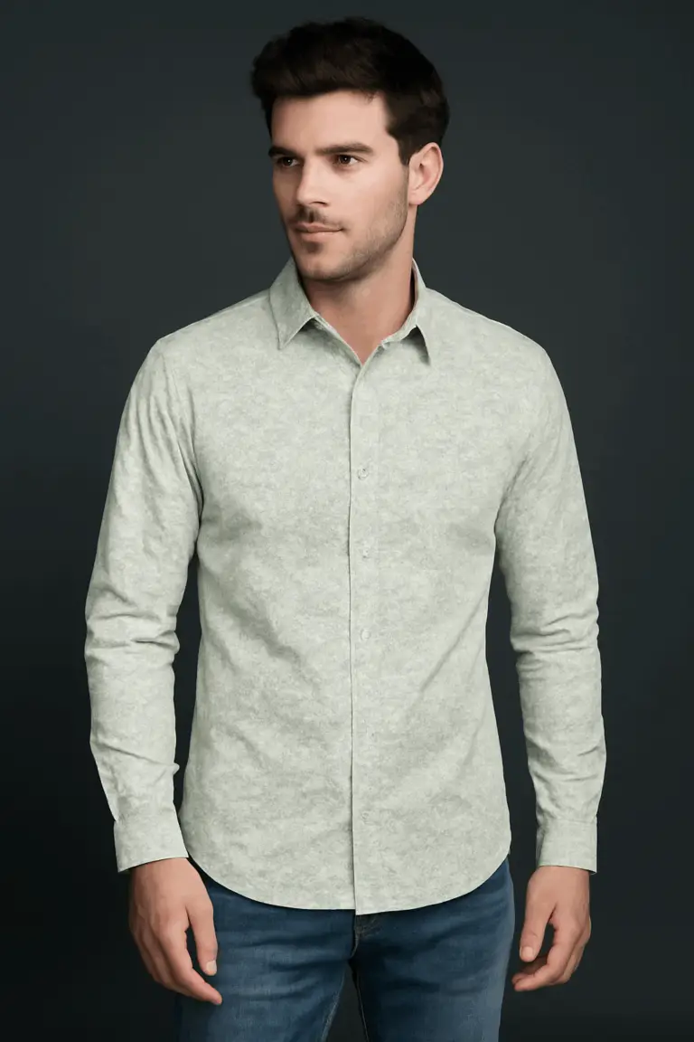 Man wearing a slim fit, full-sleeve shirt in a light sage green with a subtle micro print, paired with blue jeans against a dark background.