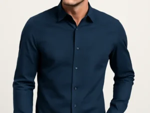 Man looking to the side, wearing a slim fit navy blue full-sleeve shirt with a subtle geometric dobby pattern, paired with blue jeans.