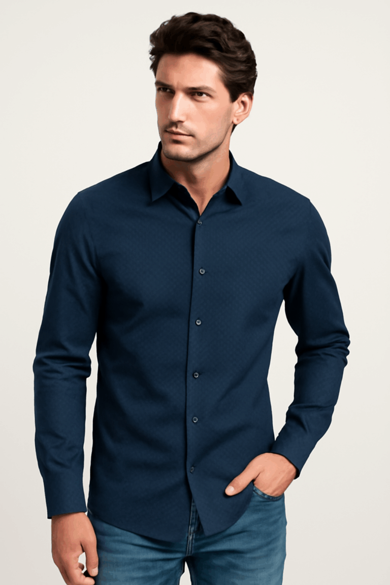 Man looking to the side, wearing a slim fit navy blue full-sleeve shirt with a subtle geometric dobby pattern, paired with blue jeans.